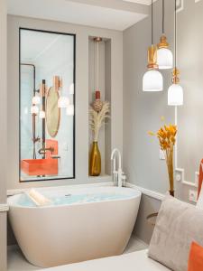 uma casa de banho com banheira, espelho e pendentes em The Orange Haussmann em Paris