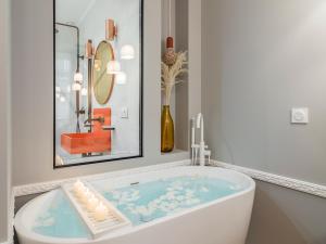 eine Badewanne im Bad mit Gemälde und Spiegel in der Unterkunft The Orange Haussmann in Paris