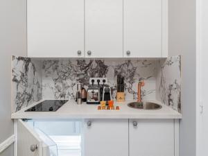 uma cozinha com armários brancos e um lavatório em The Orange Haussmann em Paris