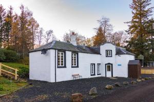 a small white house sitting on the side of a road at Dalnaglar Castle Estate in Glenshee