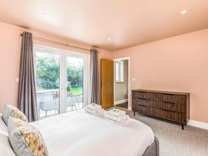 a bedroom with a bed and a large window at Pass the Keys Stylish and fresh 4 bed beach house with garden in Chichester