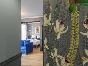ein Wohnzimmer mit einem blauen Sofa und einer Wand mit Blumen in der Unterkunft The Blue King Suite in Paris