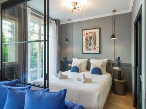 ein Schlafzimmer mit einem großen weißen Bett mit blauen Kissen in der Unterkunft The Blue King Suite in Paris