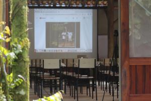 
a room filled with tables and chairs with a projector screen at Pousada Todas as Luas in Ubatuba
