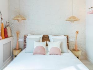um quarto com uma cama com almofadas cor-de-rosa e brancas em Pink & Wood cocoon em Paris