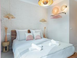 um quarto branco com uma grande cama branca com almofadas em Pink & Wood cocoon em Paris