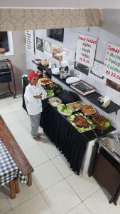 a woman standing in front of a buffet of food at Pousada São Judas Tadeu in Cachoeira Paulista