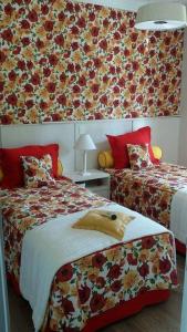 um quarto com 2 camas e um papel de parede floral em Pousada São Judas Tadeu em Cachoeira Paulista