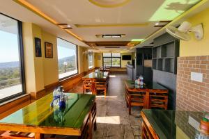a restaurant with tables and chairs and large windows at JK Hotel Dharamshala in Dharamshala