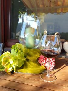 a glass of wine sitting next to a vase at Ferienwohnung MaarBurg in Ulmen