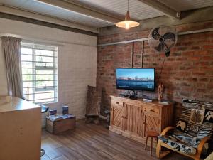 a living room with a television and a brick wall at GreenHouse Accommodation in Tulbagh