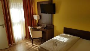 a bedroom with a bed and a desk with a television at INVITE Hotel Nürnberg City in Nürnberg