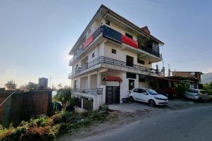 una macchina bianca parcheggiata di fronte a un edificio di JK Hotel Dharamshala a Dharamshala
