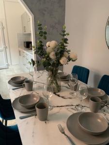 北安普敦的住宿－House of cosy dots，一张桌子,上面有盘子和玻璃杯,花瓶
