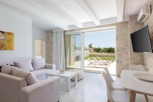 a living room with white furniture and a tv at Mythos villas in Damnoni