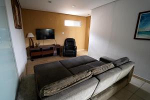 a living room with a couch and a flat screen tv at Hostel caminho da Cachoeira in Florianópolis