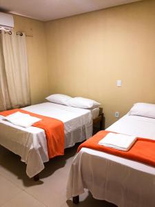 um quarto com duas camas com lençóis laranja e branco em Sunset Hotel em Carolina