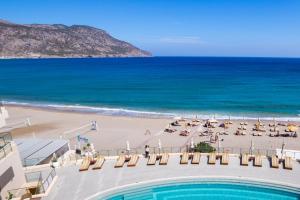 a view of a beach with chairs and a swimming pool at Konstantinos Palace in Karpathos
