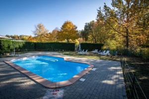 a swimming pool in a yard with chairs and trees at Albavillage Rooms & Camping in Alba