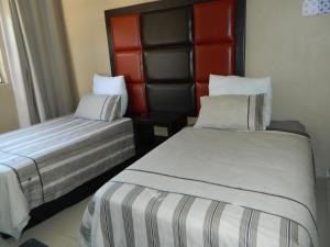 um quarto de hotel com duas camas e uma cabeceira em Sgobolo Guest House em Calcutta