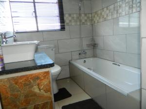uma casa de banho com uma banheira, um WC e um lavatório. em Sgobolo Guest House em Calcutta