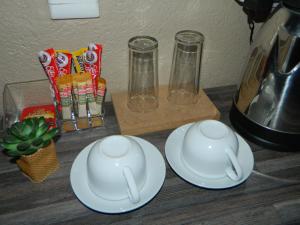 duas chávenas e pratos num balcão com um liquidificador em Sgobolo Guest House em Calcutta