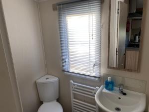 a bathroom with a toilet and a sink and a window at Paul’s place silversands in Lossiemouth