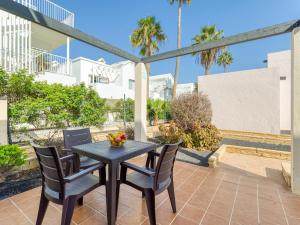 een patio met een tafel en stoelen en palmbomen bij HomeForGuest Moderno Apartamento en Corralejo in Corralejo