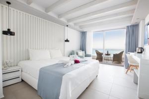 a white bedroom with a white bed and a table at Konstantinos Palace in Karpathos