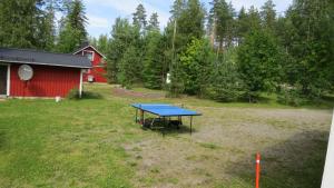 a ping pong table in a yard with a red barn at Mannimaatila Uni Lux in Punkaharju
