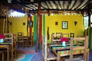 un ristorante con tavoli e sedie in legno e una parete gialla di Sagando Bungalows Zanzibar a Michamvi Kae