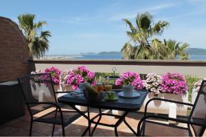 d'une table et de chaises sur un balcon orné de fleurs roses dans l'établissement Appartamento MarySol, à Alghero
