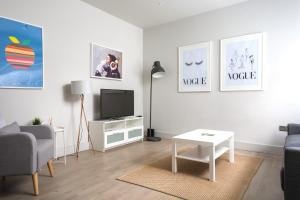 a living room with a couch and a tv at Oxford Passage Coach House in Cheltenham