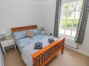 a bedroom with a wooden bed and a window at Crown Cottage in Tenby