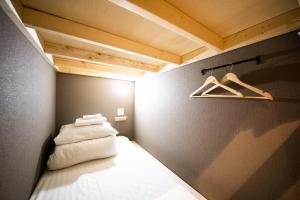 a small room with a bed and a wooden ceiling at Ten to Ten Hostel in Sapporo