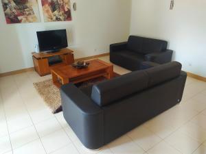 a living room with a black couch and a tv at AH - Vila Verde Private Apartment in Santa Maria