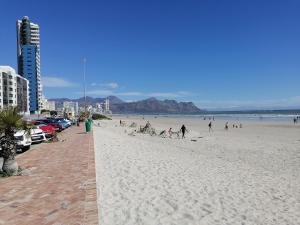 a group of people on a beach near the ocean at The Jade Somerset West Beachfront Apartment with Pool & Mountain Views in Cape Town