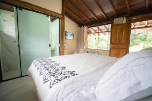 a bedroom with a large white bed and a window at Diver Village Ilhabela in Ilhabela