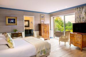 a bedroom with a bed and a television and a balcony at Château de Courban and Spa Nuxe in Courban