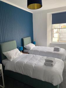 2 camas en una habitación de hotel con paredes azules en Queensberry arms hotel, en Kirkconnel