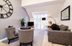 a living room with two chairs and a clock on the wall at Minster's Reach York city centre Apartments in York