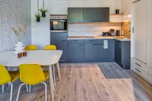 een keuken met blauwe kasten, een witte tafel en gele stoelen bij new apartment I cozy I Netflix I WLAN I near airport in Dresden