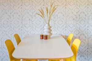 un tavolo bianco con sedie gialle e un vaso sopra di new apartment I cozy I Netflix I WLAN I near airport a Dresda