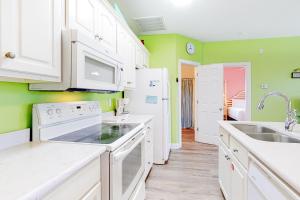 a kitchen with white appliances and green walls at Plum Cute by Meyer Vacation Rentals in Gulf Shores