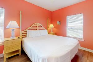a bedroom with a white bed and orange walls at Plum Cute by Meyer Vacation Rentals in Gulf Shores