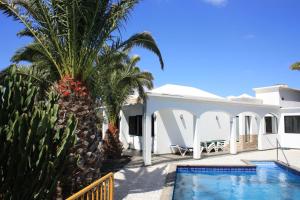 a white villa with a swimming pool and palm trees at Casa Ronda in Charco del Palo