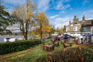 a hotel with tables and chairs next to a river at The Waterhead Inn- The Inn Collection Group in Ambleside