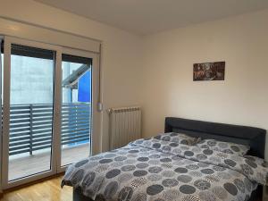 a bedroom with a bed and a sliding glass door at Dom apartmani II in Kragujevac