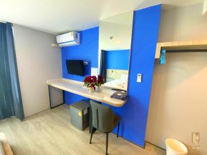a room with a blue wall and a desk with a mirror at วัน บัดเจท เชียงราย สนามกีฬา One Budget Hotel Chiangrai Stadium in Chiang Rai