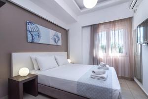 a bedroom with a white bed with towels on it at Coral Apartments in Ierapetra